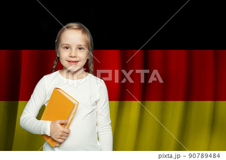 Education and school in Germany. Beautiful cute little kid girl with book against German flag Education and school in Germany. Beautiful cute little kid girl with book against German flag 90789484