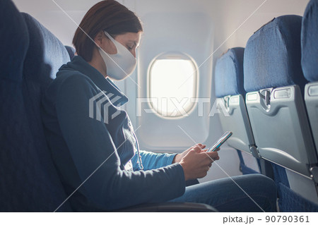 Young beautiful woman sitting at window of plane during the flight 90790361