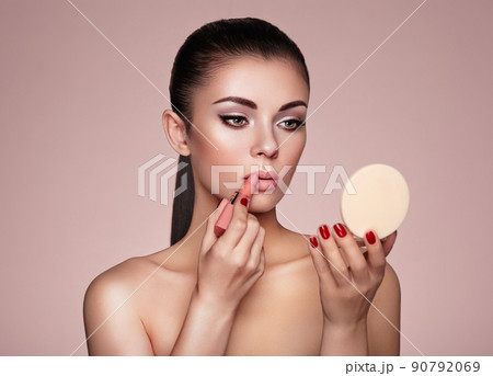 Beautiful woman paints lips with lipstick Beautiful woman paints lips with lipstick 90792069