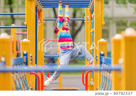 a little girl hangs on a childrens ladder on a bright playground in the park in summer 90792337