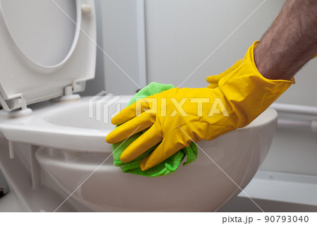 Man cleans a bathroom toilet with a green brush Man cleans a bathroom toilet with a green brush 90793040