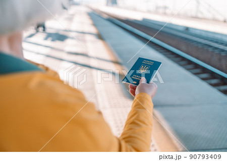 Woman hands with Ukrainian biometric passport id to travel the Europe without visas at trip train station. Modern passport with electronic chip let Ukrainians travel to European Union without visa 90793409