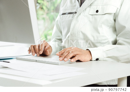 作業着を着てパソコン作業をする男性の手元 90797742