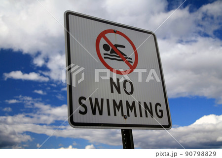 The No Swimming sign with the icon and a blue and white sky behind The No Swimming sign with the icon and a blue and white sky behind 90798829