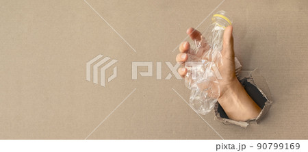 recycling concept - hand holding plastic bottle in front of cardboard hole recycling concept - hand holding plastic bottle in front of cardboard hole 90799169