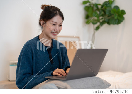 Asian girl working on laptop from home or student studying from home or freelancer. Or she is watching a video or using the Internet Asian girl working on laptop from home or student studying from home or freelancer. Or she is watching a video or using the Internet 90799210