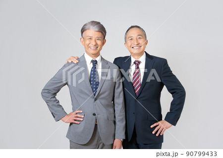 スーツを着て肩を組んで腰に手を当てるシニア男性2人のポートレート 90799433