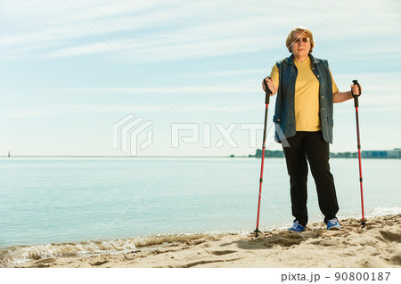 Senior woman practicing nordic walking on beach 90800187