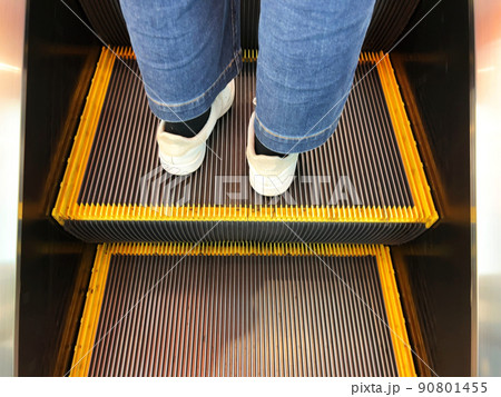 エスカレーターに乗っているスニーカーの足元 90801455