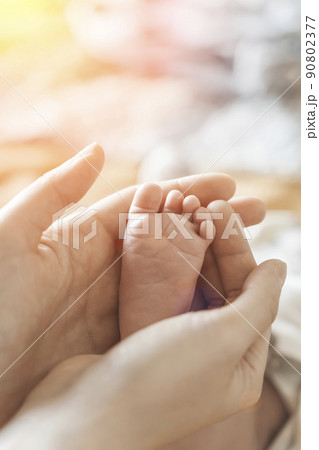 Baby feet. Mom holds with tenderness and love in his hands the small legs of a newborn. New life, parental protection, care, love, child and baby health Baby feet. Mom holds with tenderness and love in his hands the small legs of a newborn. New life, parental protection, care, love, child and baby health 90802377