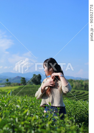 Young woman stand in the tea plantation surrounded by sky and mountain view.  Choui Fong tea plantation at Chiangrai, Thailand. 90802778