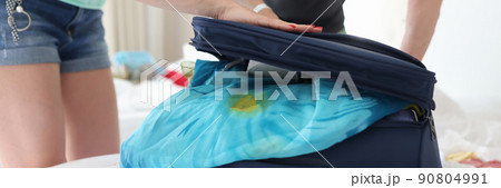 Man and woman trying to close suitcase with clothes closeup 90804991