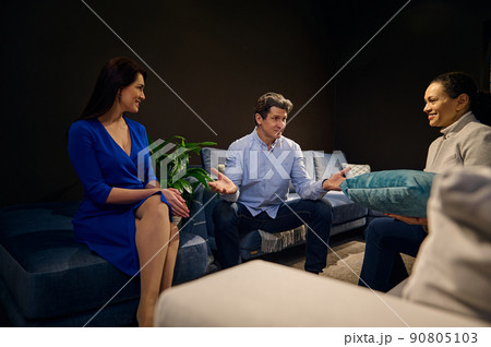 Middle-aged Caucasian couple testing different couches in a furniture design showroom 90805103