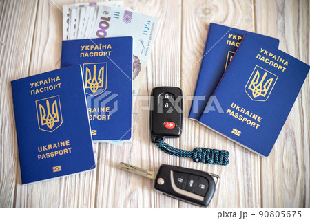 Biometric passports, car key fob alarm on wooden table background. Weekend abroad and independent car travel concept. Urgent rescue escape from Ukraine 90805675