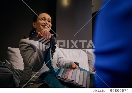 Pleasant female interior designer helps customer with their home restoration design project, demonstrates a large palette with upholstery fabric samples. Interior and home design concept Pleasant female interior designer helps customer with their home restoration design project, demonstrates a large palette with upholstery fabric samples. Interior and home design concept 90806674