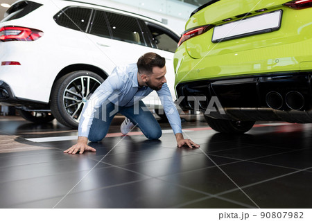 man studying the features of a new car in the showroom of a car dealership 90807982