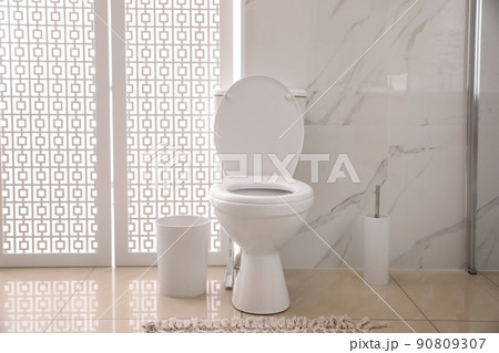 Modern white toilet bowl near marble wall indoors Modern white toilet bowl near marble wall indoors 90809307