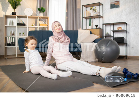 Muslim mother doing sports exercise at home together with funny little daughter 90809619