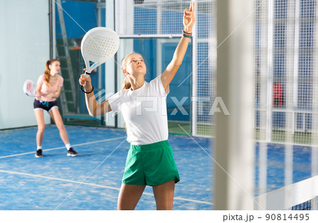 Teenage girl playing padel game on court 90814495
