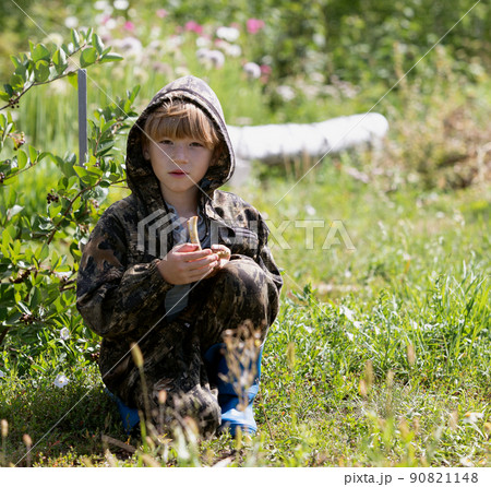 boy in camouflage suit squatting holds in his hands mushrooms boy in camouflage suit squatting holds in his hands mushrooms 90821148