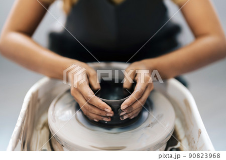 Woman working on the potter's wheel. Artisan making a cup from clay pot. Workshop of handmade modeling on the potters wheel. Woman working on the potter's wheel. Artisan making a cup from clay pot. Workshop of handmade modeling on the potters wheel. 90823968