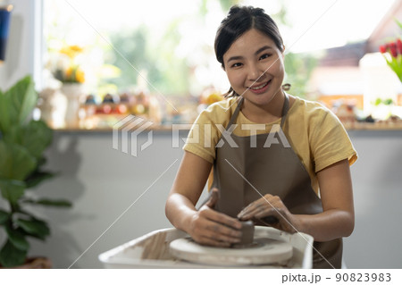 Young asian woman's hands close up, the masterful studio of ceramics works with clay on a potter's wheel. 90823983