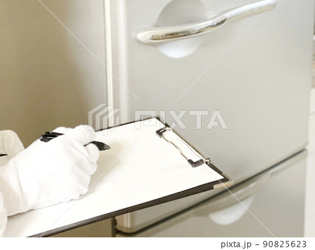 冷蔵庫を査定するクリップボードを持った白手袋の手元 冷蔵庫を査定するクリップボードを持った白手袋の手元 90825623