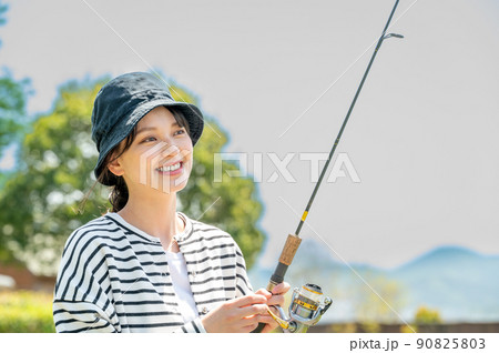 青空の下で趣味の釣りを楽しむ笑顔の若い女性 90825803