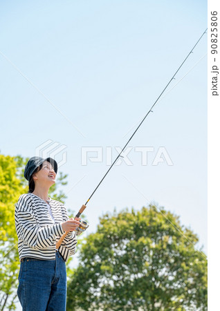 青空の下で趣味の釣りを楽しむ笑顔の若い女性 90825806