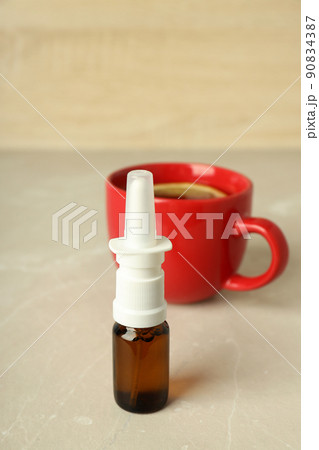 Blank bottle of nasal spray and cup of tea on light table 90834387