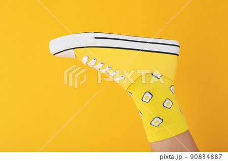 Female leg in sock with eggs and sneaker on yellow background 90834887