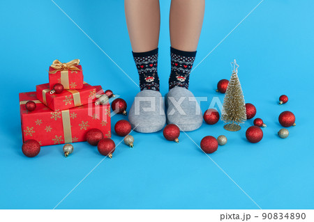 Christmas composition with female legs in Christmas socks on blue background 90834890