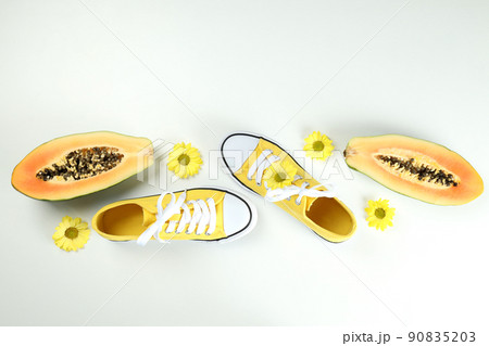 Yellow sneakers with flowers and papaya on white background Yellow sneakers with flowers and papaya on white background 90835203