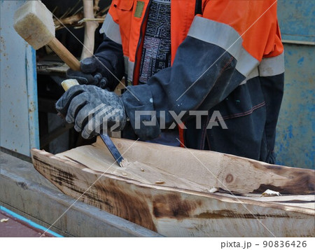 craftsman working on wood with a chisel and a mallet in a street workshop, making a tray for washing sand during artisanal gold mining from burnt wooden material craftsman working on wood with a chisel and a mallet in a street workshop, making a tray for washing sand during artisanal gold mining from burnt wooden material 90836426