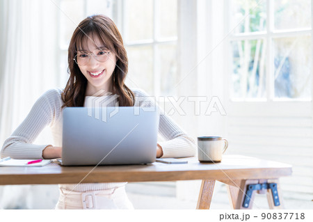 明るい部屋でノートパソコンを使う眼鏡の女性 90837718