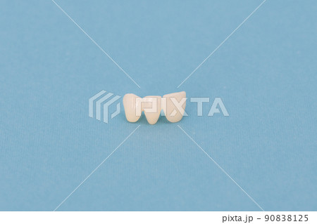 Metal free ceramic teeth implant dental crowns isolated on a blue background. Metal free ceramic teeth implant dental crowns isolated on a blue background. 90838125