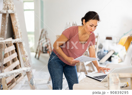 Woman construction manager checking project documentation, using laptop Woman construction manager checking project documentation, using laptop 90839295