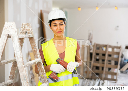 Smiling woman builder holding drill, repair works in apartment 90839335