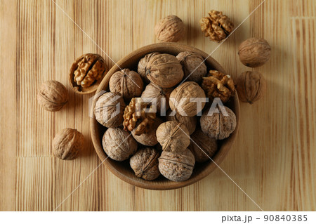 Walnuts in wooden bowl on wooden background 90840385