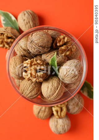 Walnuts in glass jar on orange background 90840395