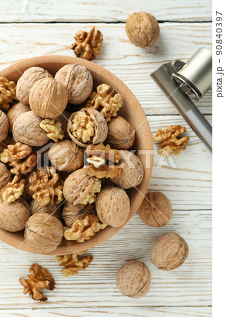 Nutcracker and bowl of walnuts on white wooden background Nutcracker and bowl of walnuts on white wooden background 90840397