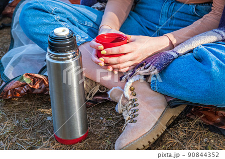 Cropped young girl sitting in a tent in the fall forest holding a cup of tea in her hands. Mental health. Time alone, contemplation. Self care Cropped young girl sitting in a tent in the fall forest holding a cup of tea in her hands. Mental health. Time alone, contemplation. Self care 90844352
