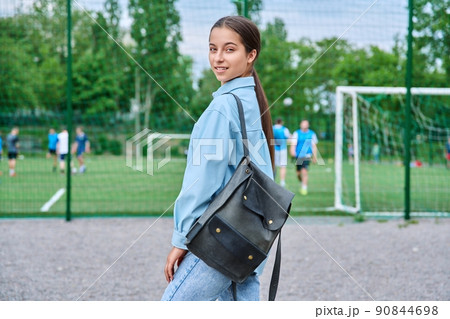 Portrait of teenage female student looking at camera, school stadium background 90844698
