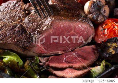 A piece of meat grilled in a cast-iron pan with vegetables 90846085