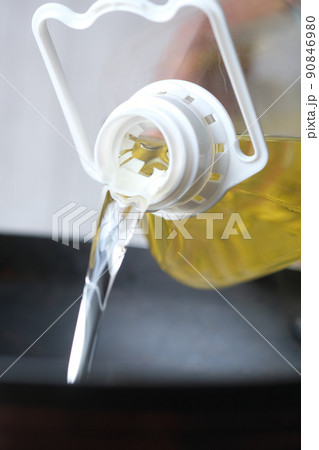 Pouring vegetable oil into frying pan. Pouring vegetable oil into frying pan. 90846980