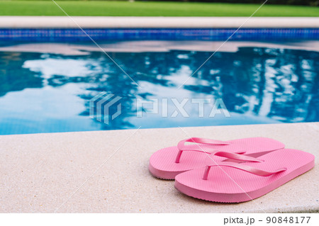 Pink flip flops for pool or beach on grass with pool bottom. Pool water texture. to use text. summer objects. Pink flip flops for pool or beach on grass with pool bottom. Pool water texture. to use text. summer objects. 90848177