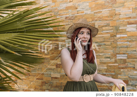 young red-haired girl, calling the hotel reception on her summer holiday. travel and leisure. tourist in a tropical resort. 90848228