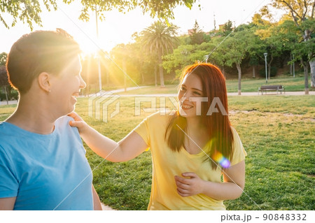 two great friends chatting and strolling happily, in a city public park at sunset. young girls enjoying the summer outdoors. concept of friendship and companionship. two great friends chatting and strolling happily, in a city public park at sunset. young girls enjoying the summer outdoors. concept of friendship and companionship. 90848332