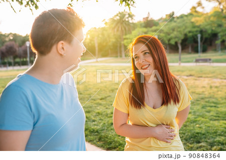 side image two great friends chatting and strolling happily, in a city public park at sunset. young girls enjoying the summer outdoors. concept of friendship and companionship. 90848364