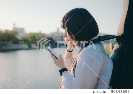 ギターとスマートフォン持った制服姿の女子高生と街 90848692